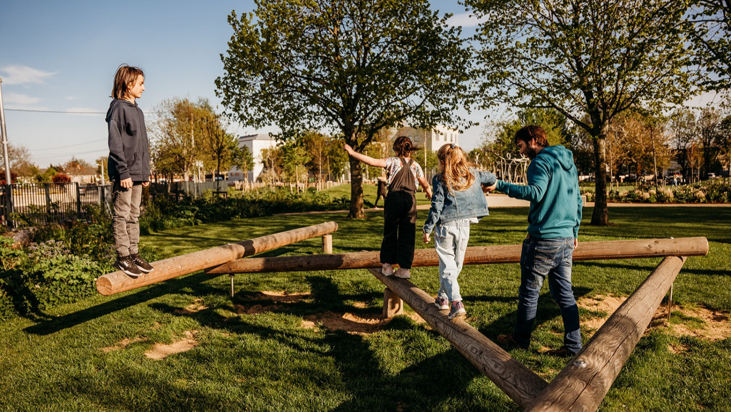 Teenagers and Children balancing on natural play equipment at Ballyfermot People's Park in Ireland