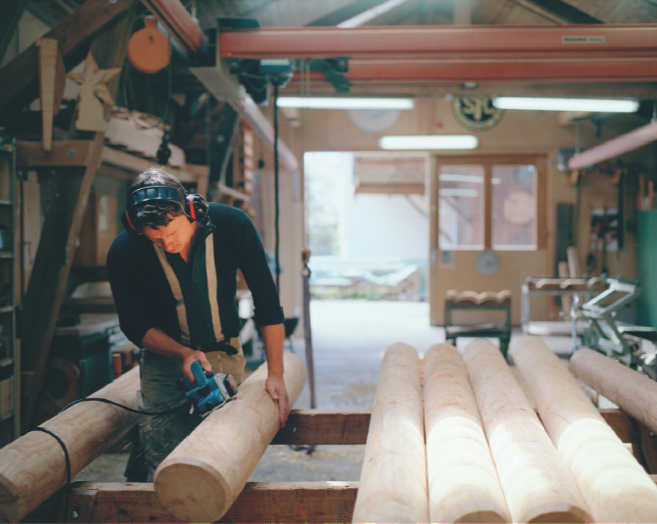 Man sanding large wooden poles